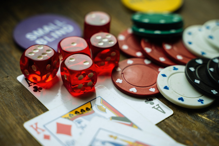 A deck of playing cards scattered on a table alongside a pair of dice and a pile of casino coins